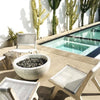 A concrete bowl fire pit near a pool and garden designed by King Garden Design