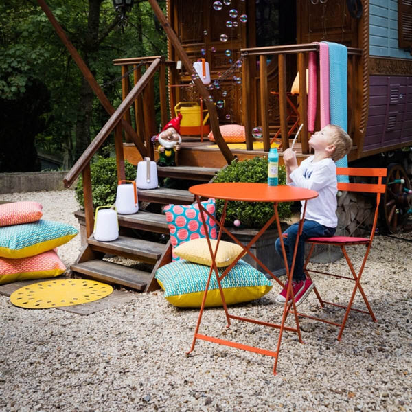 Fermob Bistro Round Table in the yard with a kid playing with bubbles